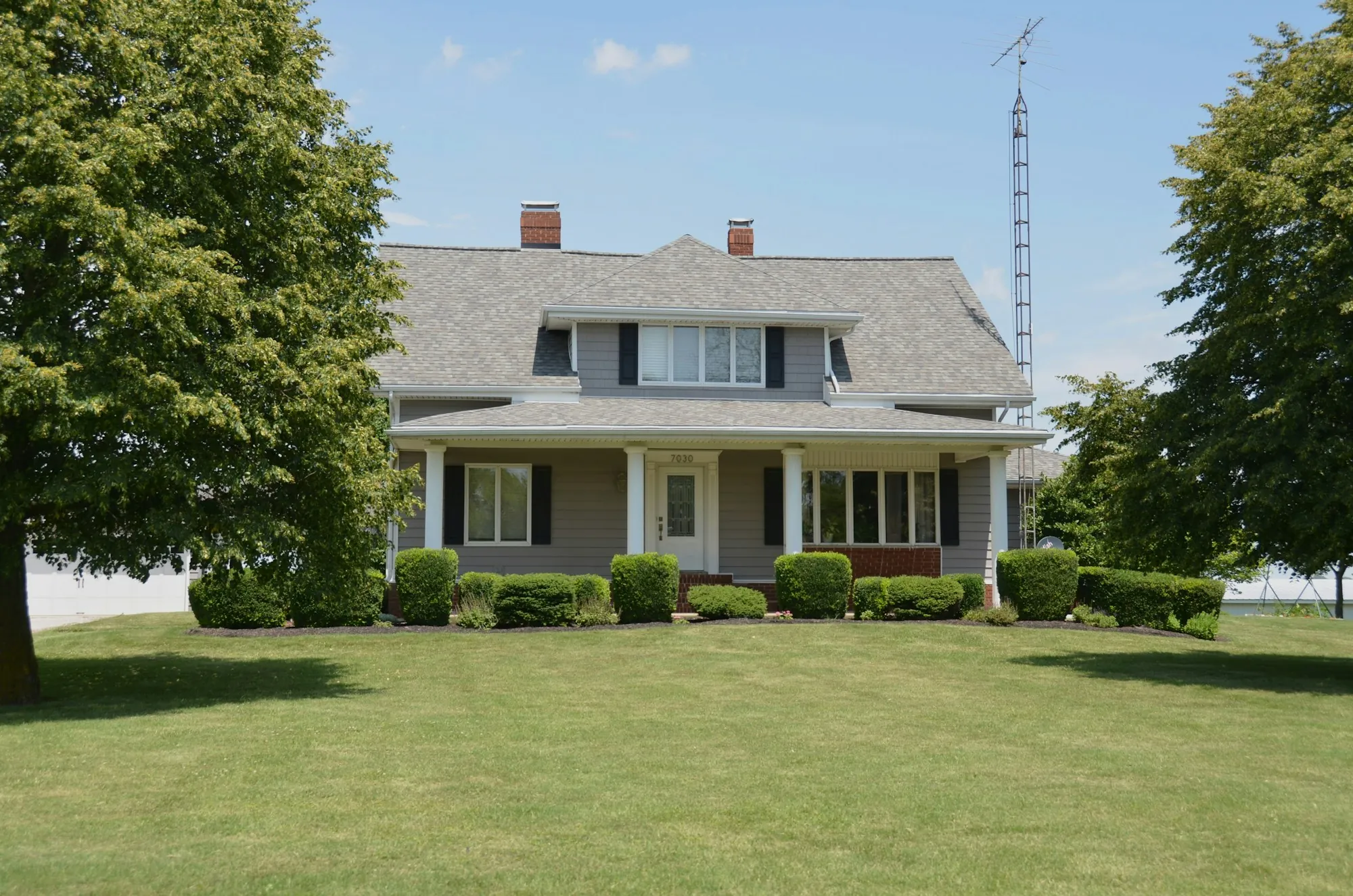 Two-story farmhouse with a covered front porch and a wide lawn