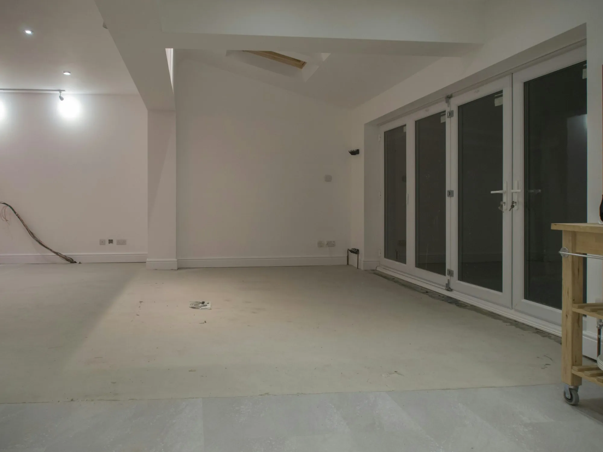 Lower-level room cleared for finishing, with new French doors and a bare floor