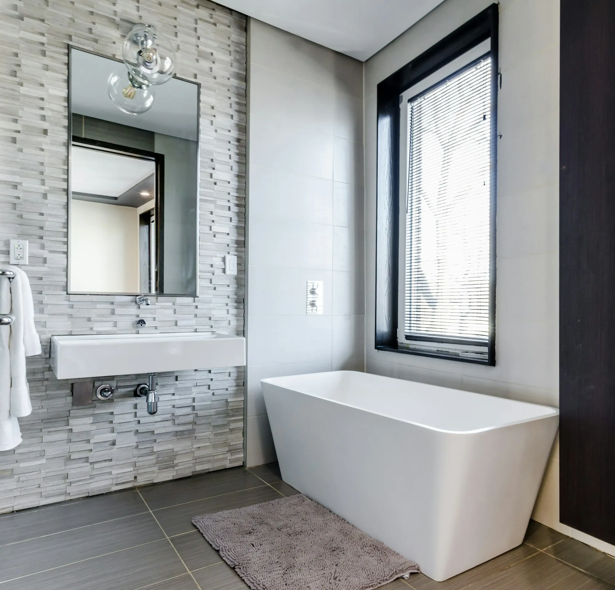 Bathroom with a freestanding tub, stacked stone accent wall and wall-mounted sink