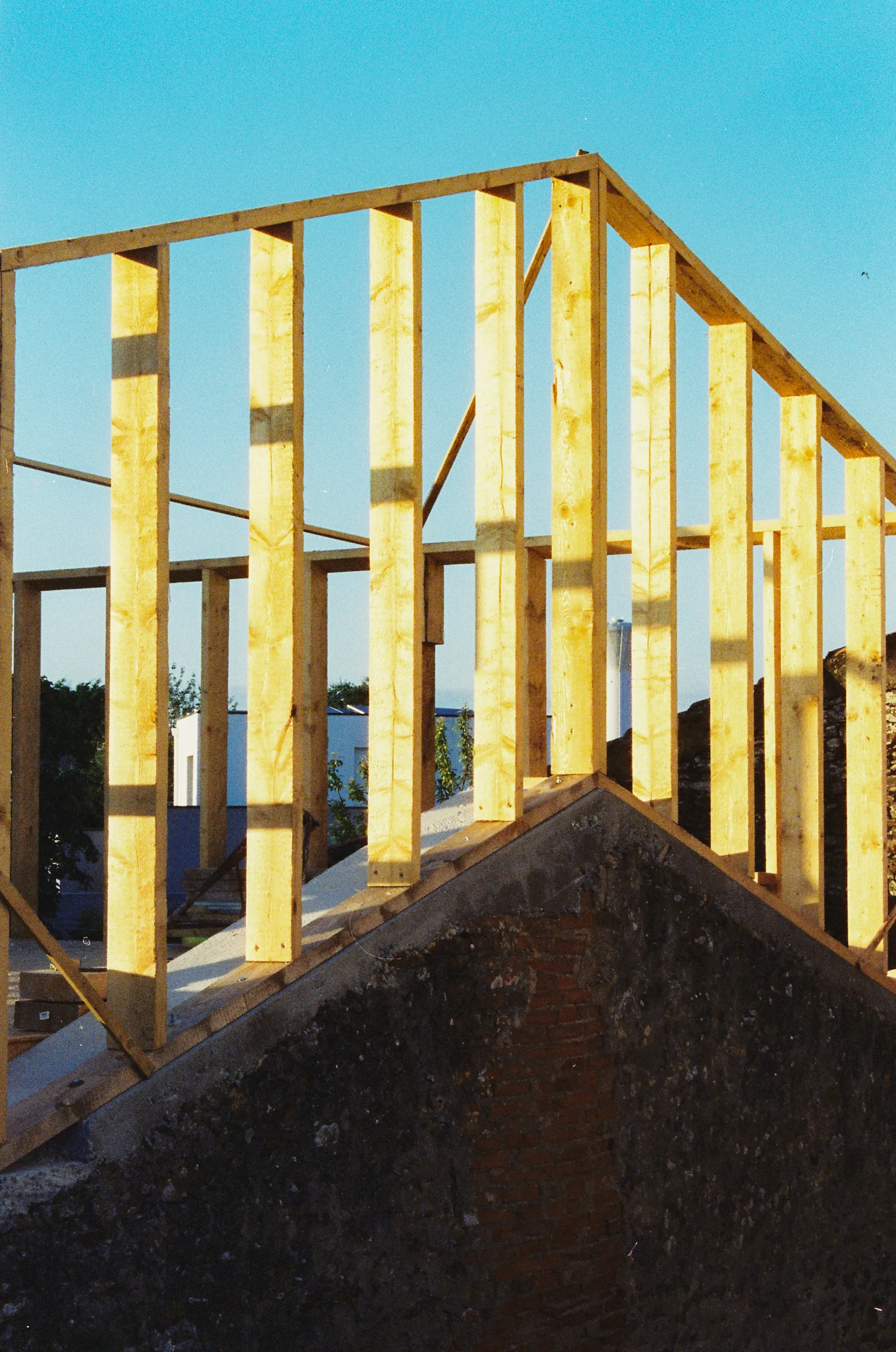 New wood wall framing rising above an existing roofline