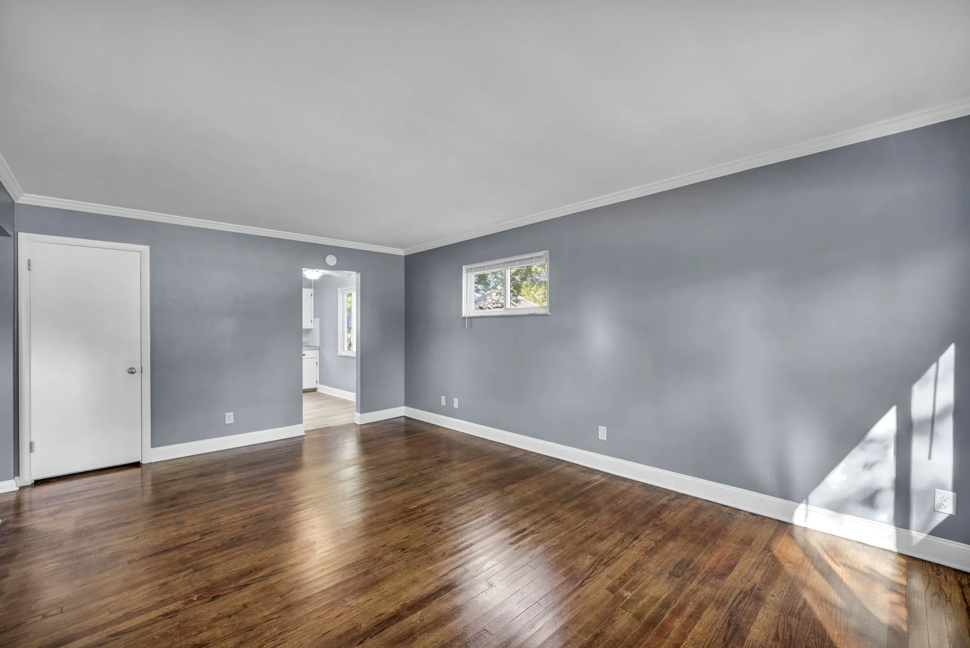 Freshly painted gray-blue room with white trim and hardwood floors