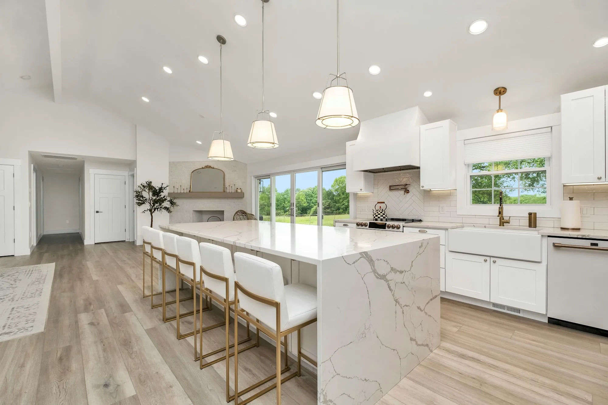 Remodeled white kitchen with a waterfall quartz island, pendant lights and bar stools