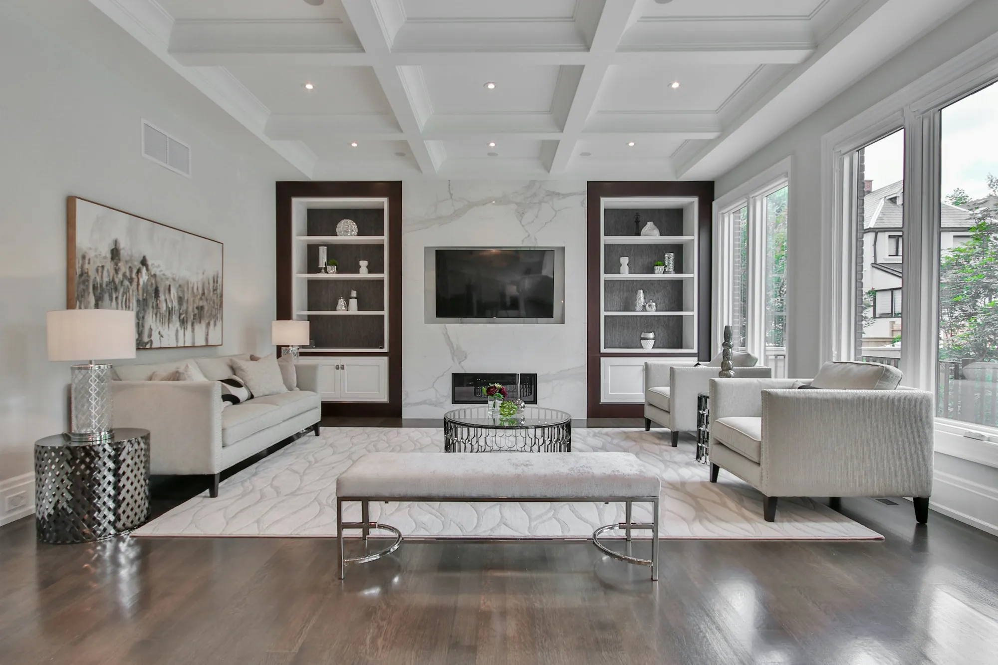 Living room with a coffered ceiling, marble fireplace wall and built-in shelves